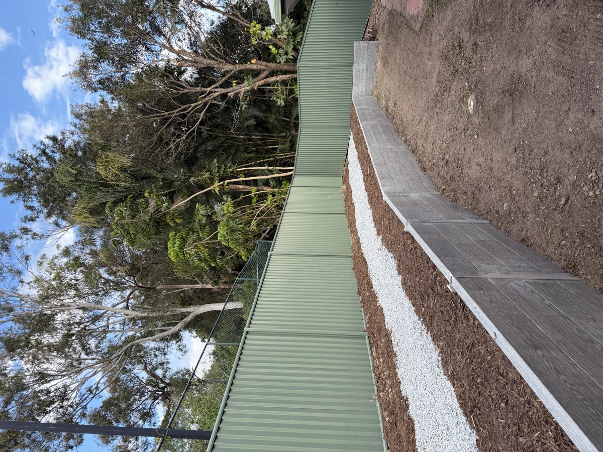 Retaining wall backfilled with drainage gravel and beds planted
